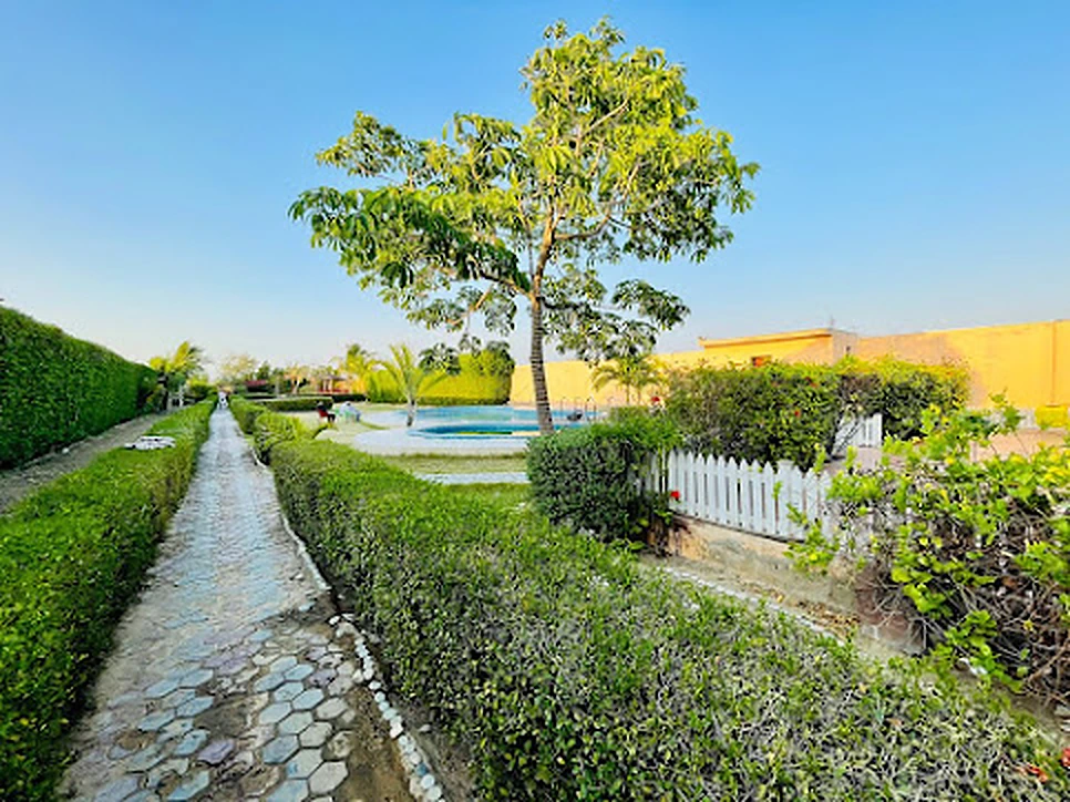 Stone garden walkway lined with hedges leading to the pools at Agha Farmhouse