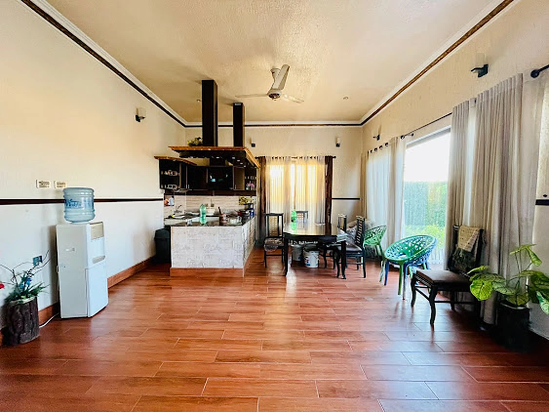 Spacious indoor hall with wooden floors, dining table and open kitchen at Agha Farmhouse